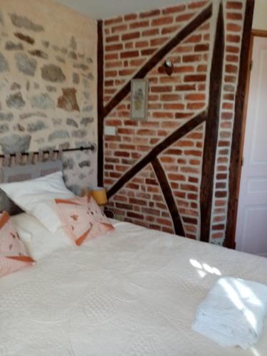 uma cama num quarto com uma parede de tijolos em Chambre Rdc em Saint-Aubin-le-Monial