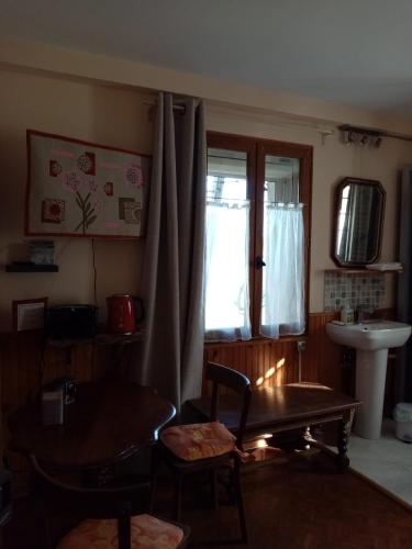 uma sala de estar com uma mesa, um lavatório e uma janela em Chambre Rdc em Saint-Aubin-le-Monial