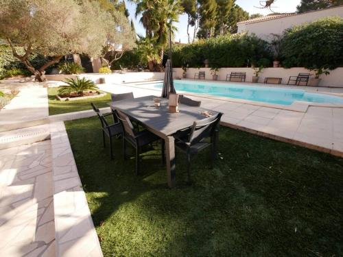 - une table et des chaises dans l'herbe à côté de la piscine dans l'établissement Villa Portissol tout à pied, à Sanary-sur-Mer