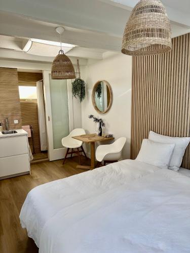 1 dormitorio con cama blanca y mesa en Oranje Nassau aan Zee Studio, en Zandvoort