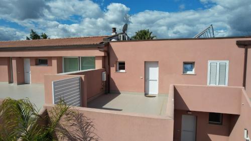 a pink house with a gate and a fence at Rubino apparthotel - Portorosa in Furnari