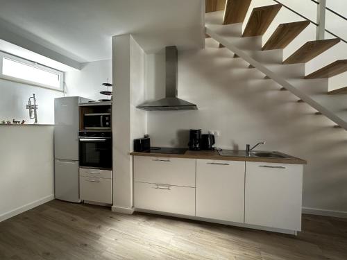 una cocina con armarios blancos y una escalera en La Bonne Etoile, en Châtelaudren