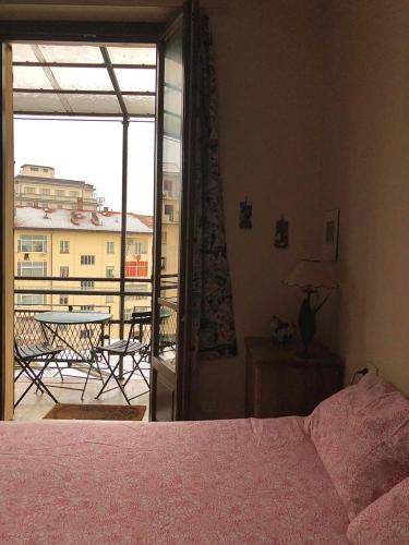 a bedroom with a bed and a balcony with a table at casa silvio pellico in Cuneo