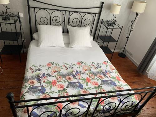 a bed with a floral bedspread and two pillows at Le Médoc de Clémence in Lamarque