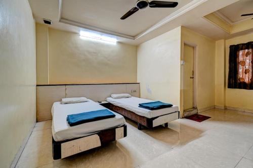 two twin beds in a room with a ceiling at Hotel Vikrant in Pune