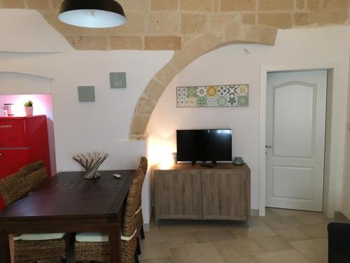 a living room with a dining room table and a tv at Casa Chicchina in Oria