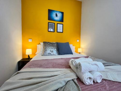 a bedroom with a large bed with a yellow wall at Encantador Madrid Val Izq in Madrid