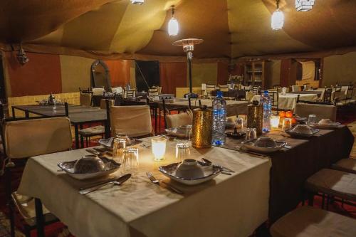 a group of tables in a tent with plates and drinks at Royal Sands Camp - Erg Chigaga Luxury Camp in Mhamid