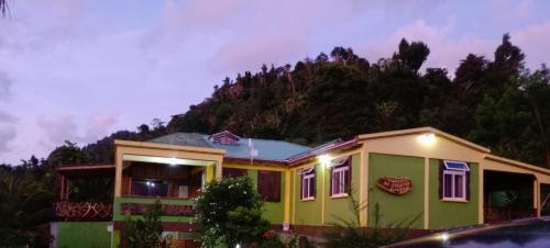 a house with a mountain in the background at Serenity Lodges Dominica in Marigot