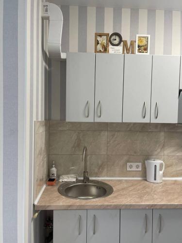 a kitchen counter with a sink and white cabinets at Sea 406 in Odesa
