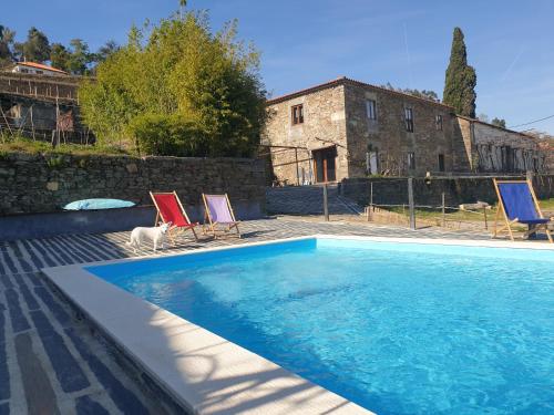 a swimming pool with two chairs and a house at Quinta de Sobre a Fonte Charming Apartments - traditional winery in Fontelas