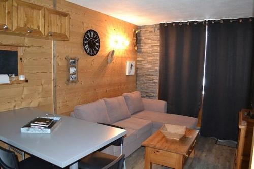 salon z kanapą i zegarem na ścianie w obiekcie Appartement Valfréjus Thabor A pieds de pistes w mieście Modane