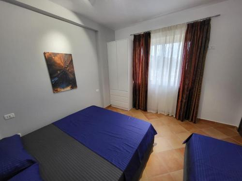 Un dormitorio con una cama azul y una ventana en Julia's Apartment in Golem Beach, en Golem