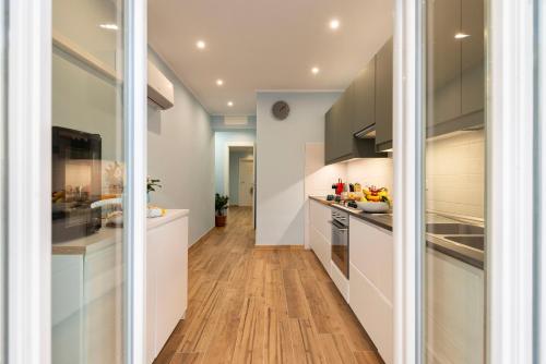 a kitchen with white cabinets and wood floors at RomeCookSea Guest House in Lido di Ostia