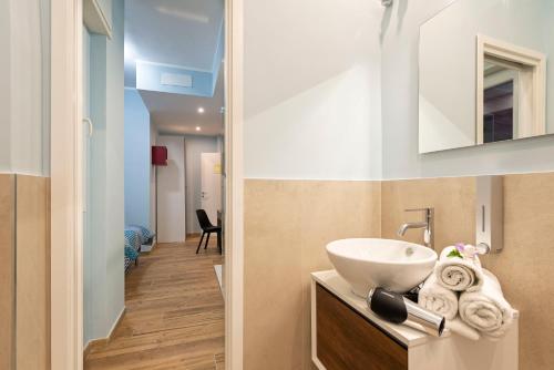 een badkamer met een wastafel en een spiegel bij RomeCookSea Guesthouse in Lido di Ostia