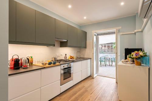 a kitchen with white cabinets and a door leading to a patio at RomeCookSea Guest House in Lido di Ostia