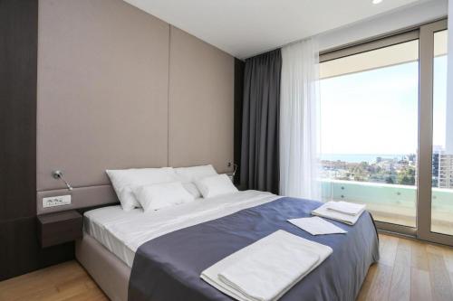 Apartments Lux sea view في بودفا: غرفة نوم بسرير كبير مع نافذة كبيرة