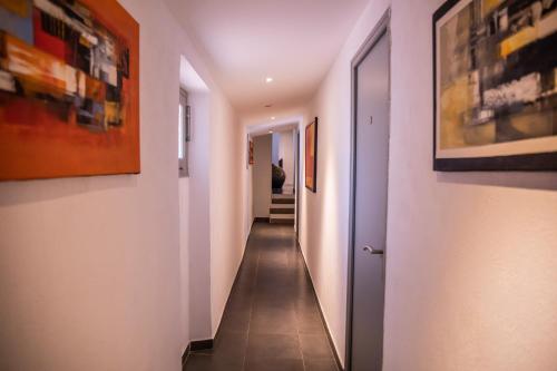 a hallway with white walls and tile floors and paintings at Auberge Sainte Marguerite in La Garde