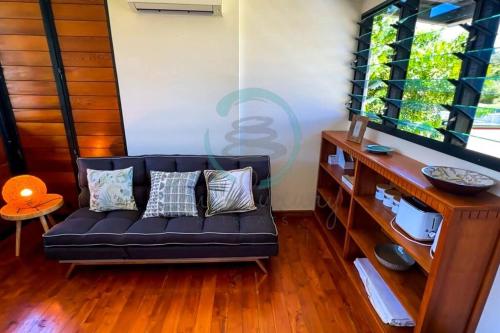 a black couch in a living room with a window at Zenhouse: 6-BR Balinese Tropical Oasis in Nightcliff Central in Nightcliff