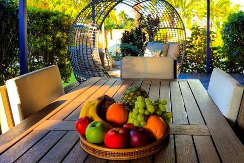 a bowl of fruit on a wooden table on a patio at Zenhouse: 6-BR Balinese Tropical Oasis in Nightcliff Central in Nightcliff