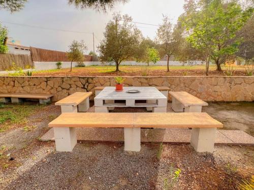 a picnic table and two benches in a park at Bonita Casa con piscina privada y amplio jardin in Sant Francesc de s'Estany
