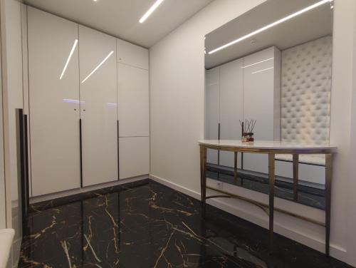 a dressing room with white cabinets and a wooden table at Premium Sky Jacuzzi Apartment in Klaipėda