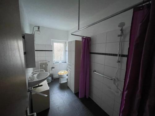 a bathroom with a toilet and a purple shower curtain at Pension Bärbel Neelen in Hameln
