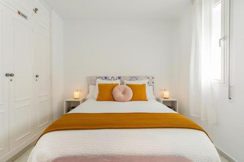 1 dormitorio blanco con 1 cama grande y 2 almohadas rosas en Sherryflat Atípika, en Jerez de la Frontera