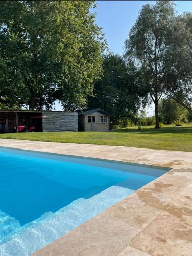 une piscine bleue avec une maison en arrière-plan dans l'établissement VILLA TARA, à Luigné