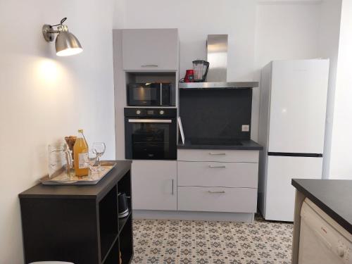 une cuisine avec des appareils blancs et un comptoir noir dans l'établissement La Maison de Léonie, à Péronne