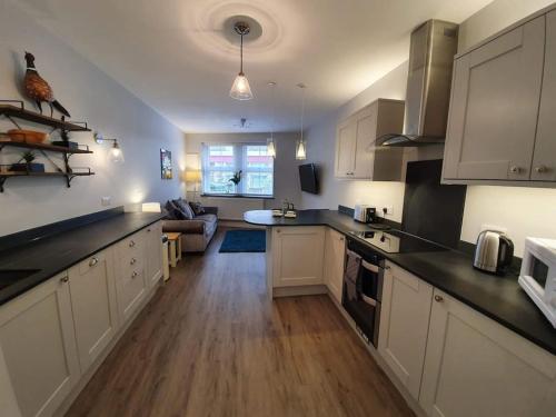 a kitchen with white cabinets and a living room at Lynton old town, Central ground floor 1 bed apart. in Lynton