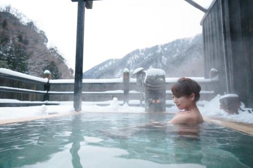 a young girl in a hot tub with snow at Hakkei in Maniwa