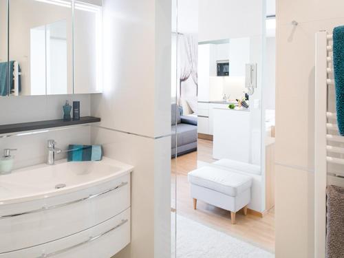 a white bathroom with a sink and a chair at Appartement VIDA in Graz