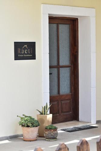 a door to a white building with potted plants at Raeti Cretan Guesthouse in Moírai