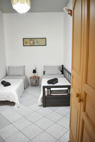 a room with two beds and a table and a window at Raeti Cretan Guesthouse in Moírai