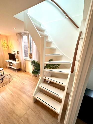 a white spiral staircase in a living room at Wellness at Sea in Egmond aan Zee