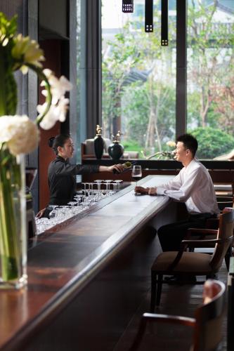 two men sitting at a bar in a restaurant at Tonino Lamborghini Hotel Suzhou in Suzhou