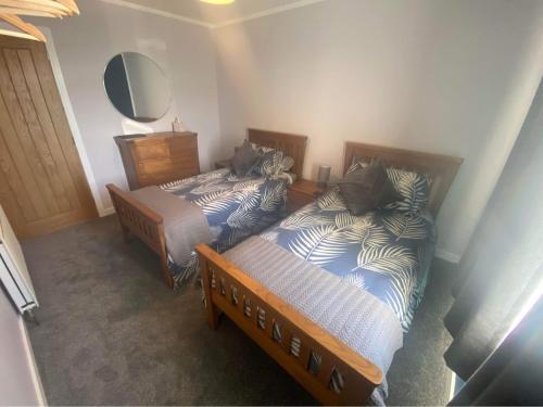 two twin beds in a room with a mirror at Sunnybank, Kensaleyre in Portree