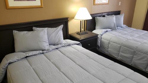 a hotel room with two beds and a lamp at West Texas Inn & Suites Midland in Midland