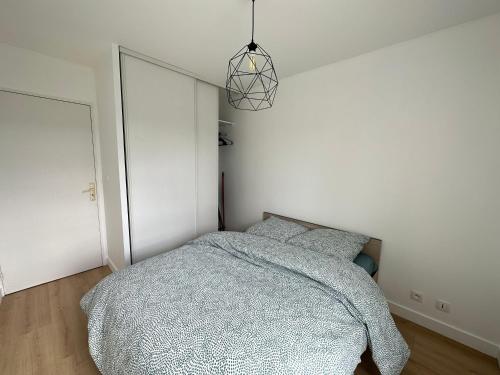 a bedroom with a bed and a pendant light at Appartement Caen in Caen