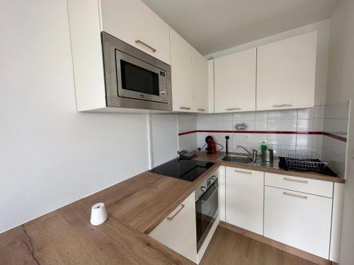 uma cozinha com armários brancos e um micro-ondas em Appartement Caen em Caen