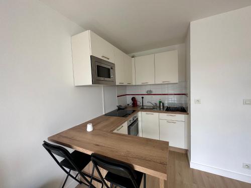 a kitchen with white cabinets and a wooden counter top at Appartement Caen in Caen