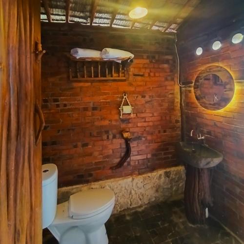 a bathroom with a toilet and a brick wall at Ama Awa Resort in Kemadang