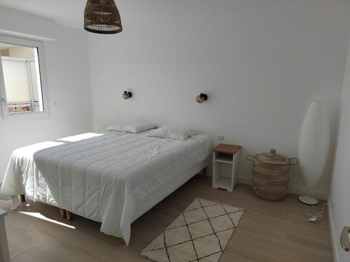 a white bedroom with a bed and a window at Ker Romain - Sea View - 3 bedrooms Appt in Saint Malo