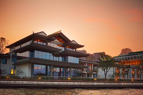 a large building with a sunset in the background at Tonino Lamborghini Hotel Suzhou in Suzhou