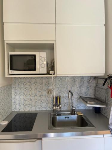 une cuisine avec un évier et un micro-ondes dans l'établissement appartement bord de mer avec piscine, à Cagnes-sur-Mer