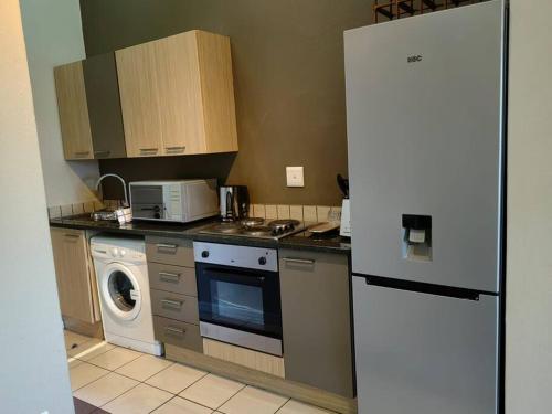 a kitchen with a refrigerator and a washing machine at Tranquility facing Steyn City in Sandton