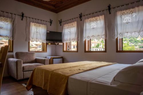 a bedroom with a bed and a chair and windows at Hotel Borklad in Berat