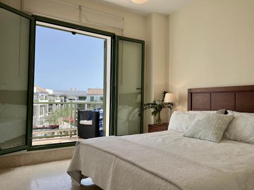 a bedroom with a bed and a large window at ATICO EN SOTOGRANDE in Sotogrande