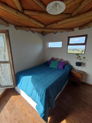 una camera con letto blu in una stanza con soffitti in legno di Alojamientos CUYEN para 2 o 3 personas Playa Quequen y El Faro a Quequén